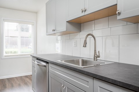 a kitchen with white cabinets and a sink and a faucet