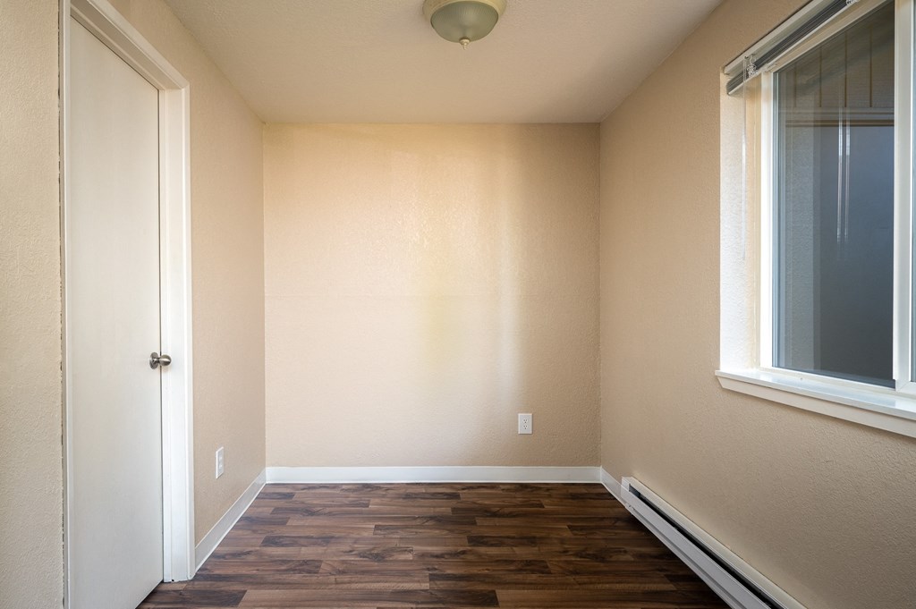 an empty room with wood flooring and a window