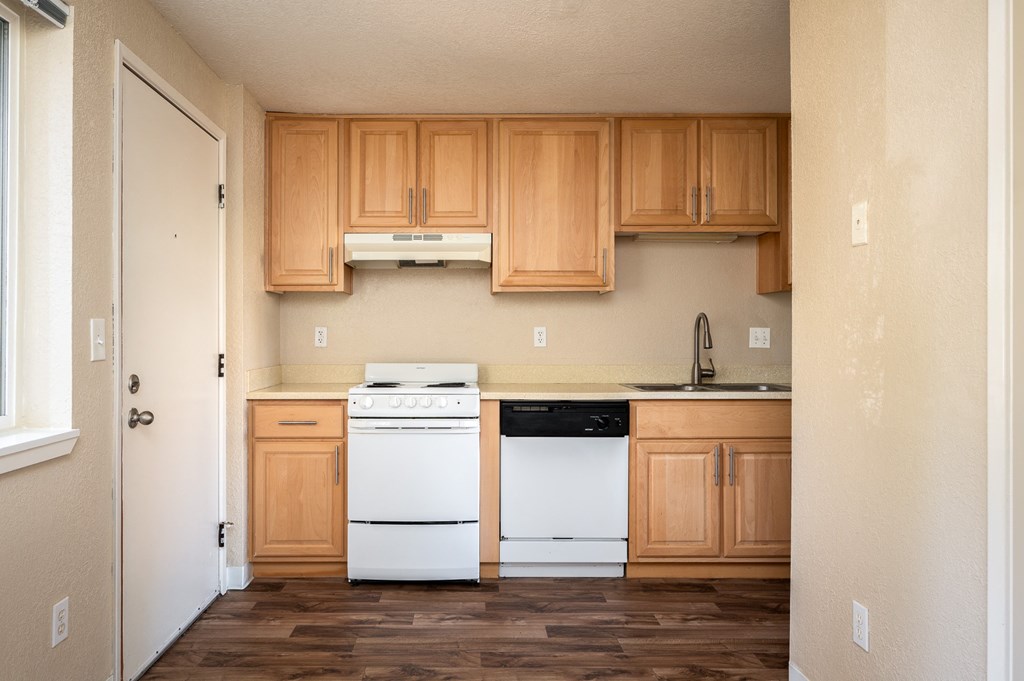 an empty kitchen with white appliances and wooden cabinets