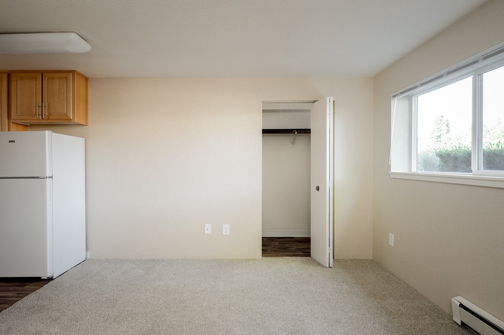 an empty room with a refrigerator and a window