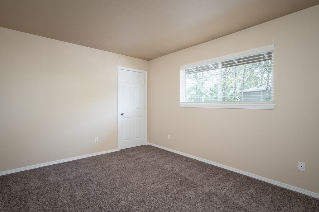 an empty bedroom with carpet and a window