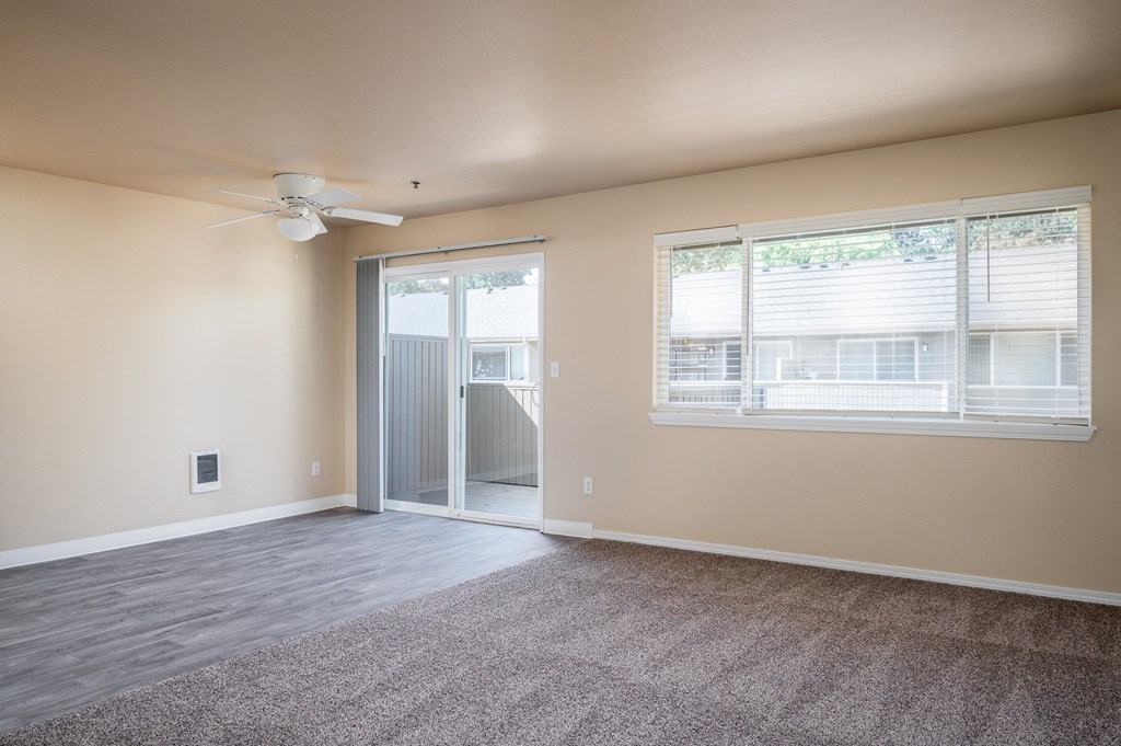an empty living room with a window and a ceiling fan