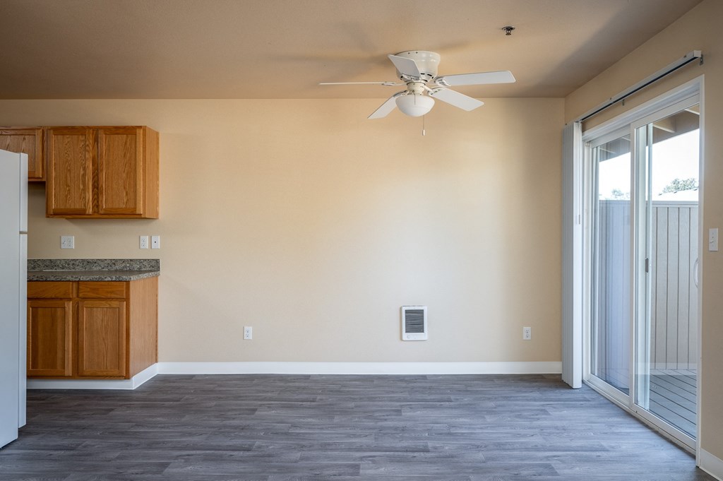 an empty living room with a ceiling fan and a window