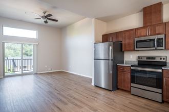 a kitchen and living room with wood floors and a sliding glass door leading to a balcony