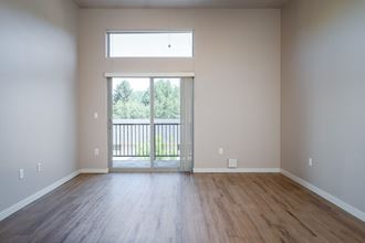an empty living room with a sliding glass door leading to a balcony