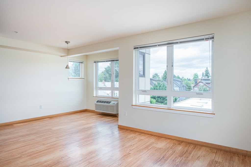 an empty living room with wood floors and a large window