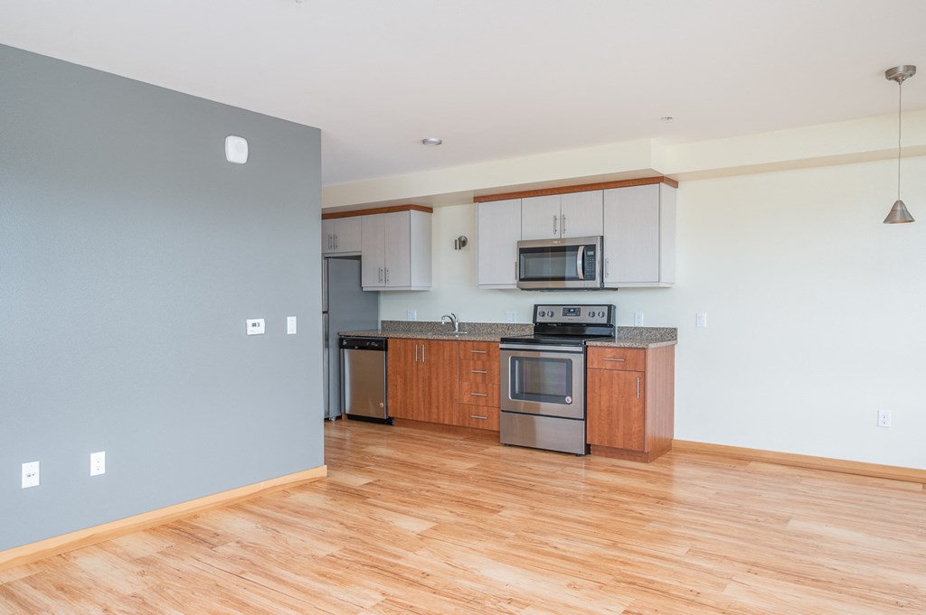 an empty kitchen with wood flooring and stainless steel appliances