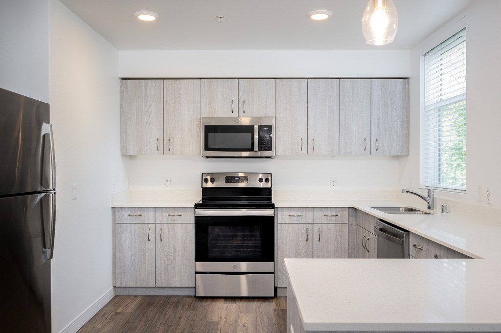 2-Bedroom Apartments in Vancouver, WA - 134th Street Lofts - Kitchen with Wood-Plank Vinyl Flooring, Stainless Steel Energy Efficient Appliances, Light Wood-Tone Cabinetry, White Quartz Countertops, a