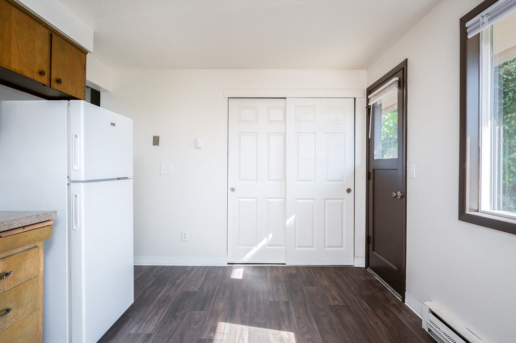 an empty kitchen with a white refrigerator and a white door