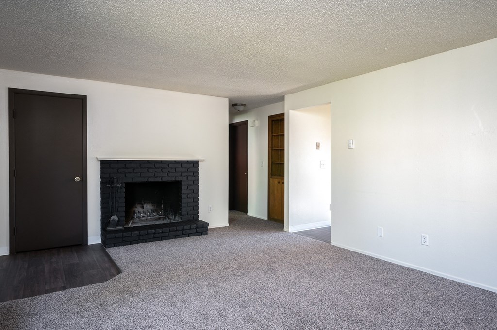 an empty living room with a fireplace and white walls