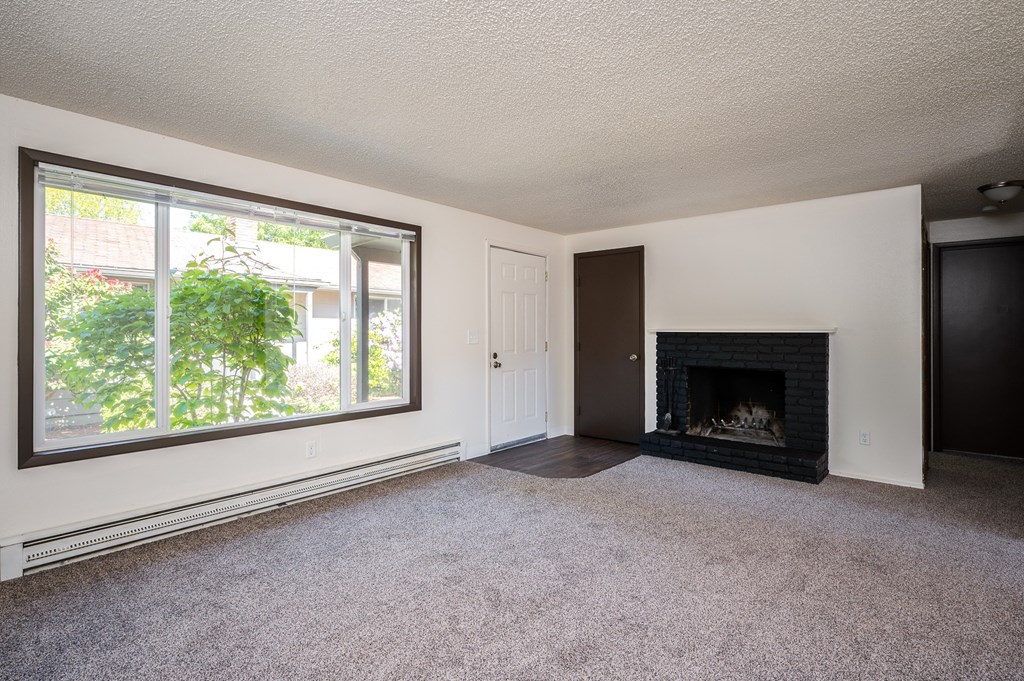 an empty living room with a fireplace and a large window