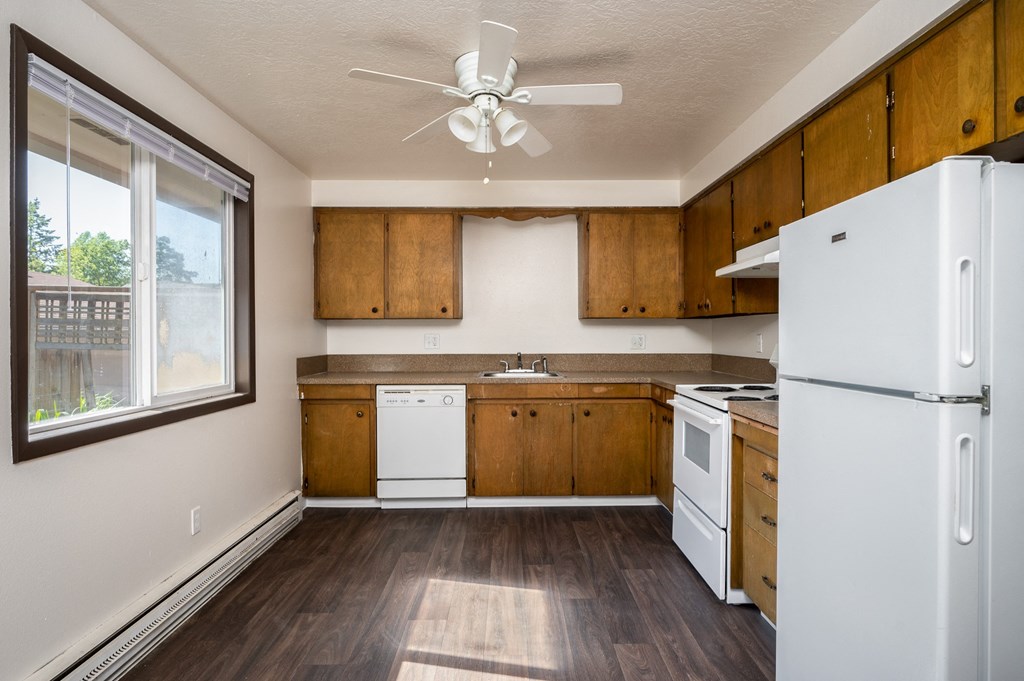 an empty kitchen with white appliances and wooden cabinets