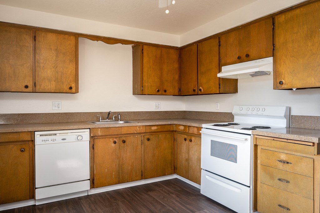 an empty kitchen with white appliances and wooden cabinets