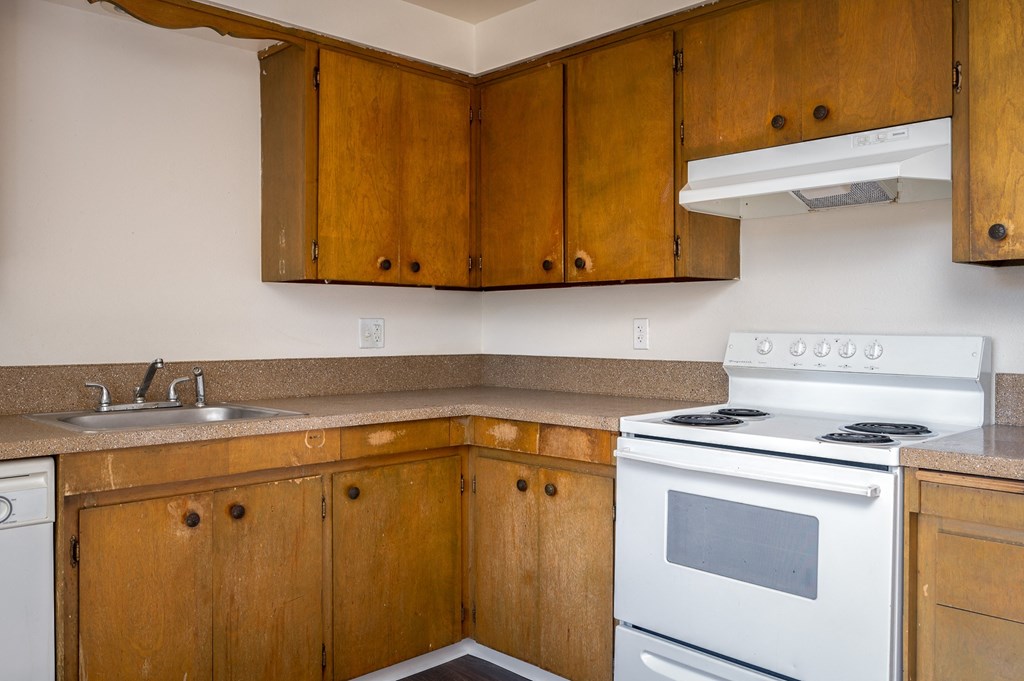 an empty kitchen with white appliances and wooden cabinets