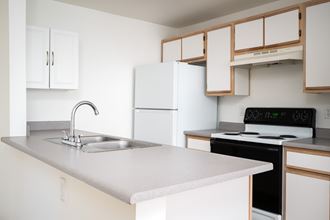an empty kitchen with white appliances and a sink
