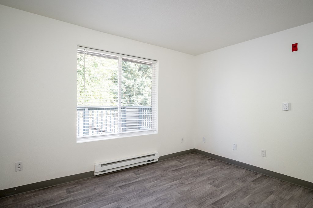 an empty room with a large window and wood flooring