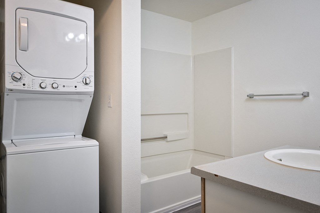 a bathroom with a washer and dryer in it and a sink and tub