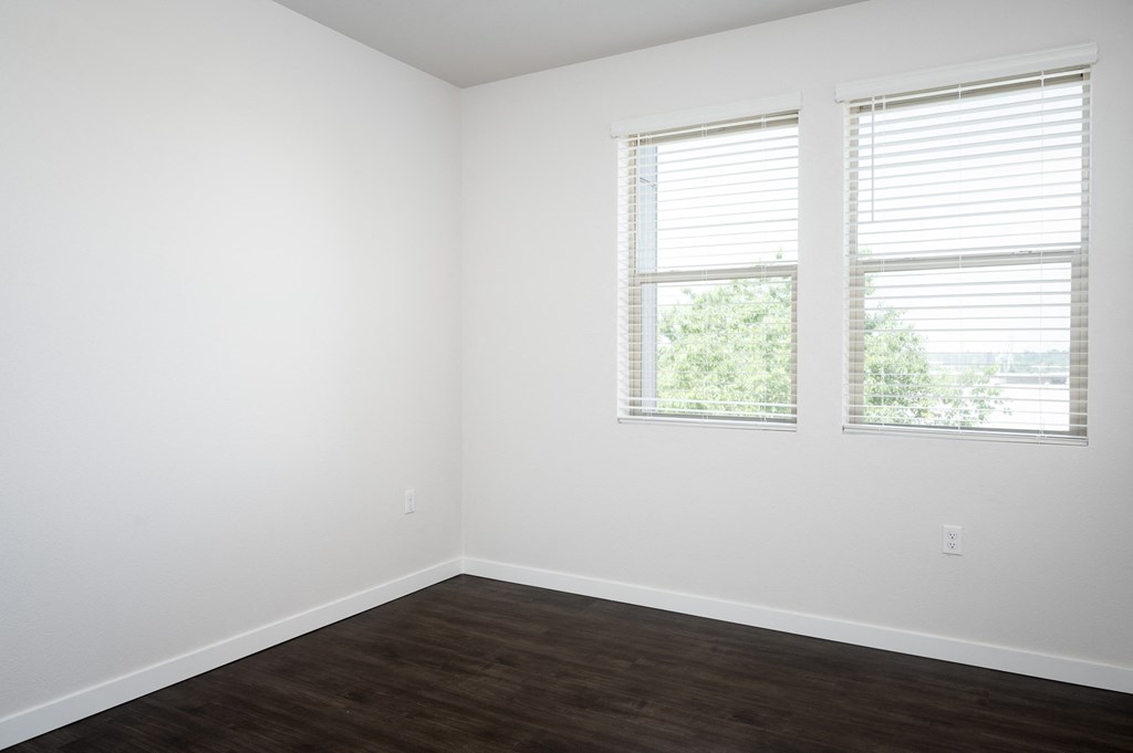 a bedroom with two windows and white walls