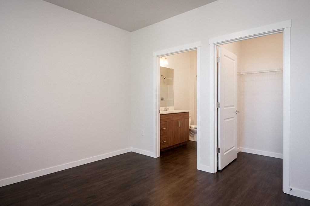 a bedroom with white walls and wood flooring