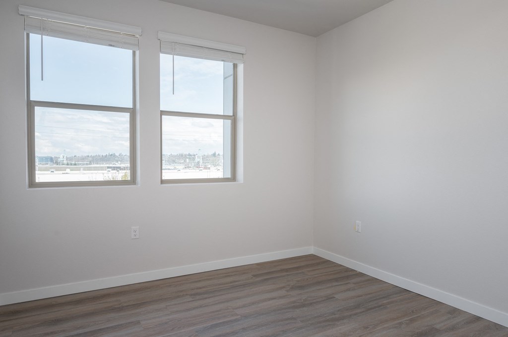 an empty room with three windows and a wooden floor