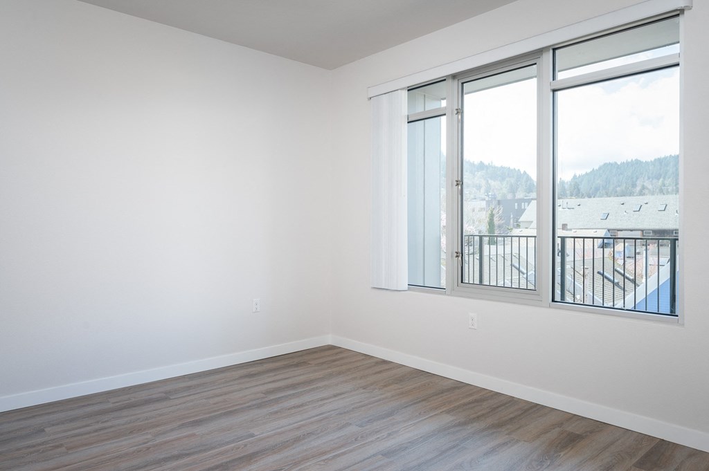 a bedroom with hardwood floors and white walls