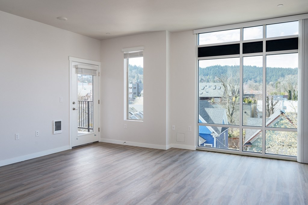 an empty living room with hardwood floors and large windows