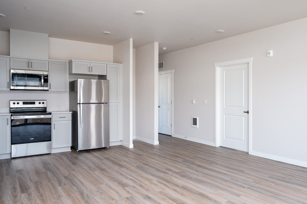 a kitchen and living room with white walls and wood floors