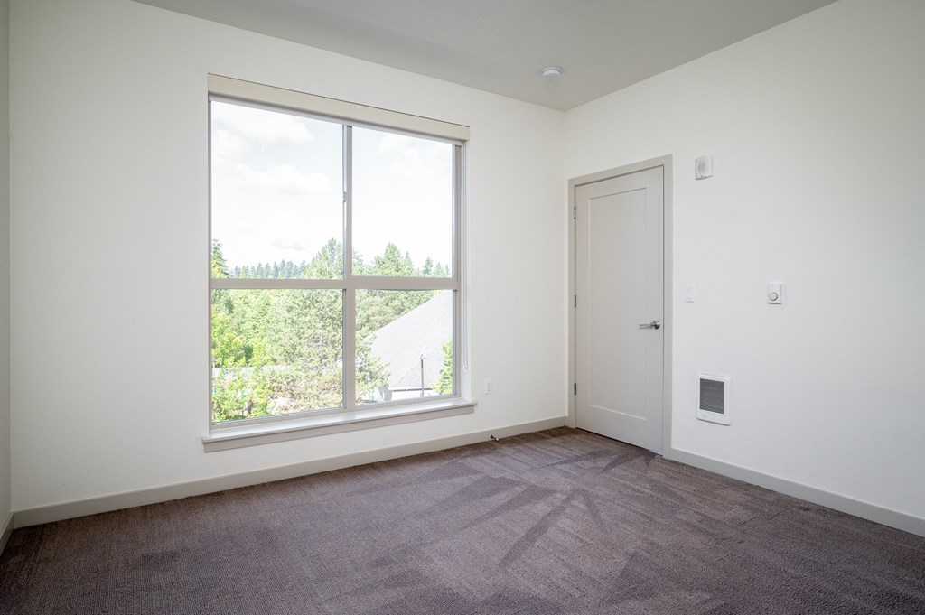 an empty living room with a large window and a door