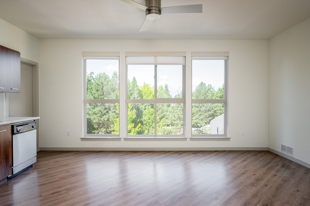 an empty living room with large windows and wood flooring