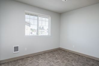 a bedroom with a window and a carpeted floor