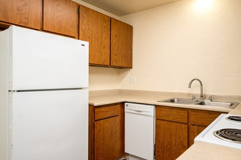 A white refrigerator stands in a kitchen with wooden cabinets.