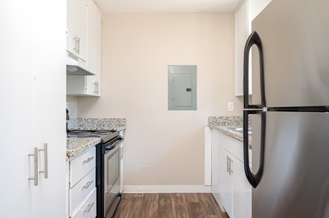 A kitchen with a stainless steel refrigerator and white cabinets.