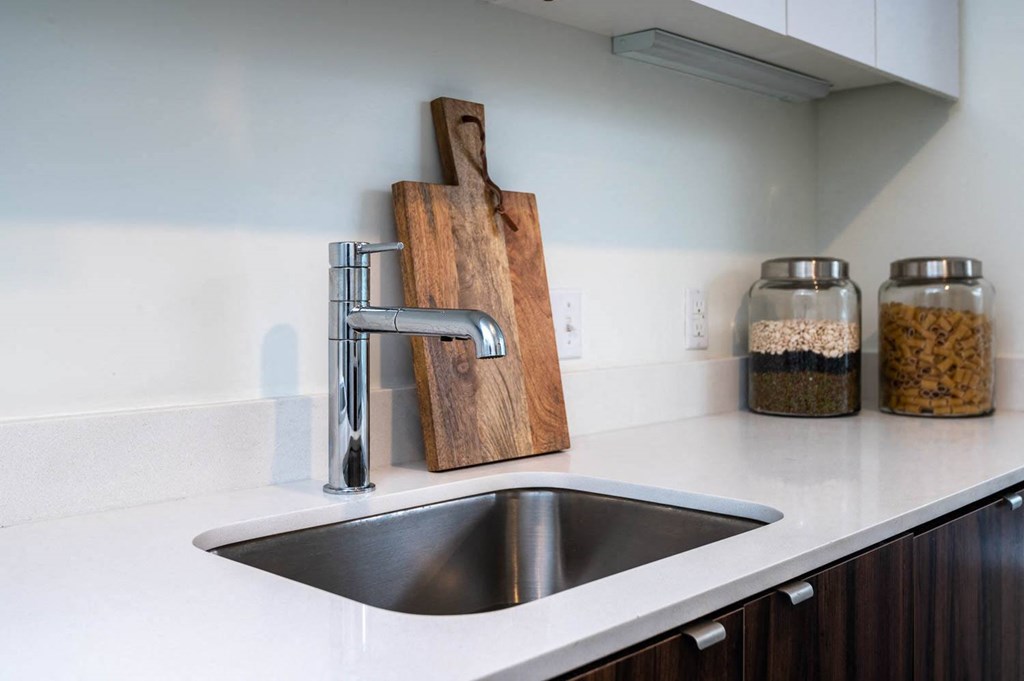 a kitchen sink with a wooden cutting board on the wall