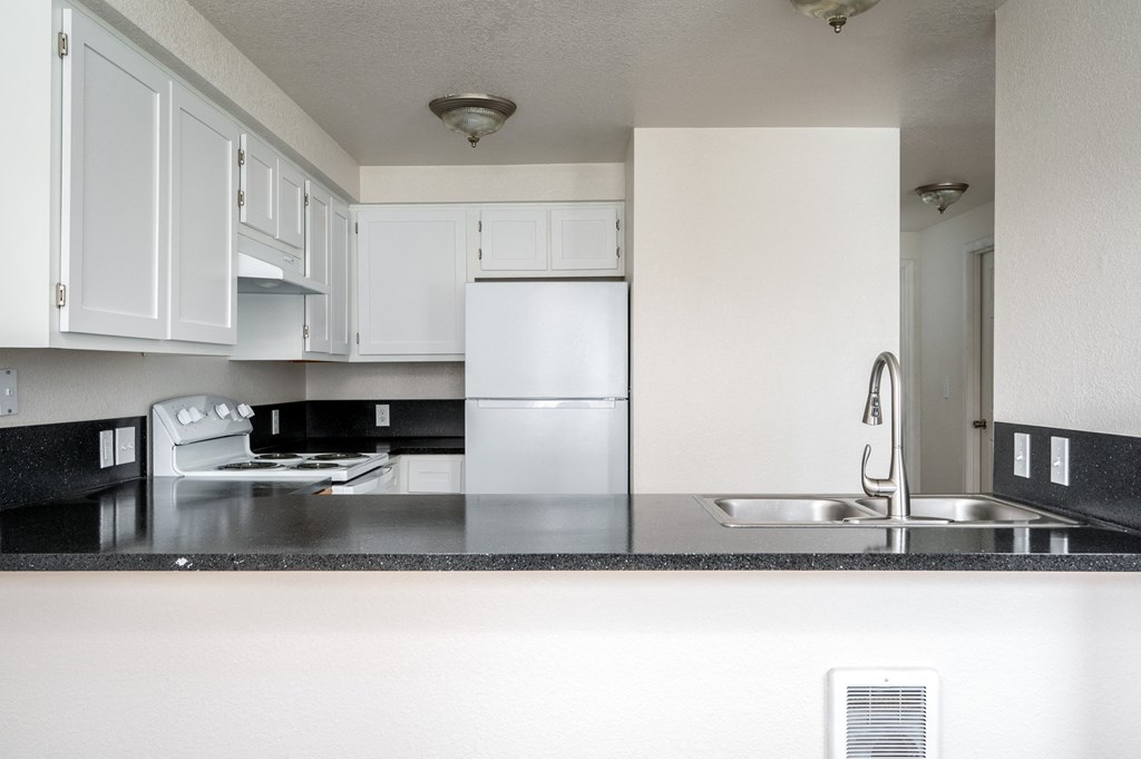 a kitchen with white cabinets and a black counter top