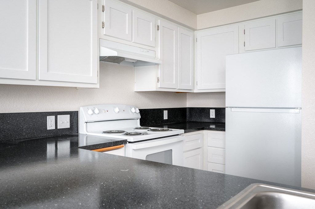 a kitchen with white appliances and black counter tops