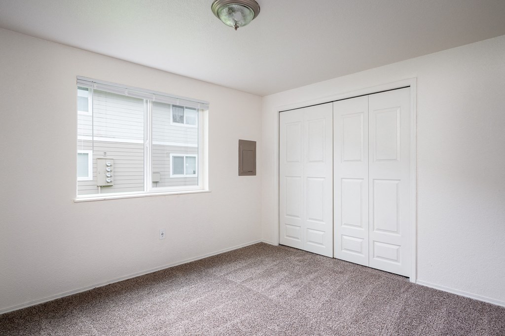 an empty room with carpet and a window and a closet