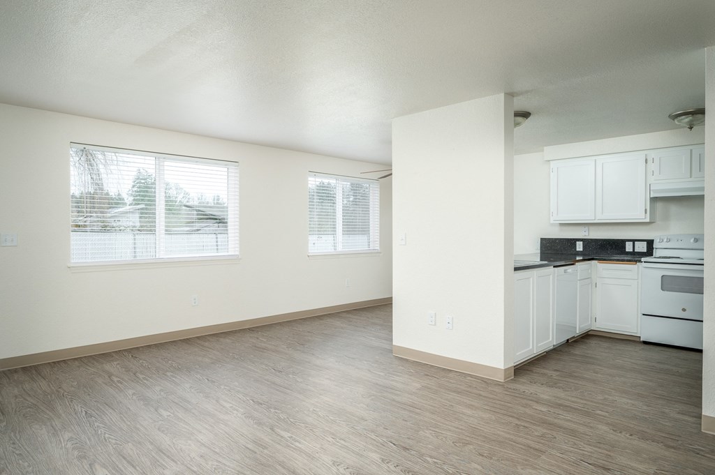 an empty kitchen and living room with white cabinets and white appliances