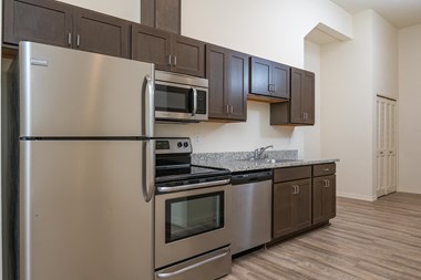 Midtown apartments kitchen. Dark cabinetry, stainless steel appliances including refrigerator, stove/oven, microwave and dishwasher.