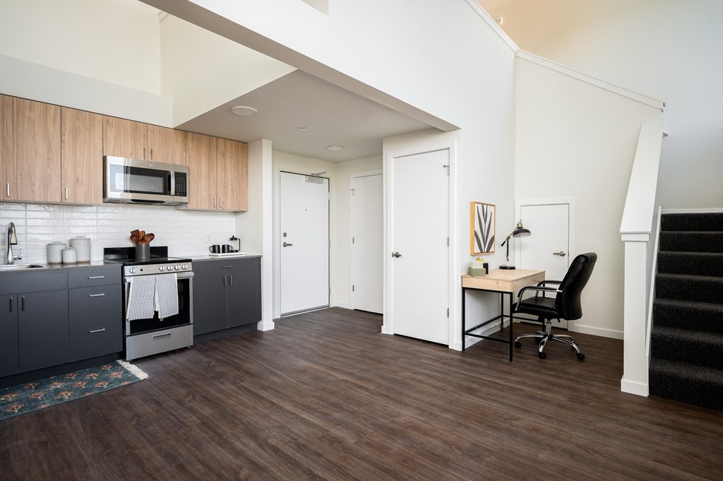 View of studio living room, kitchen and stairway to loft