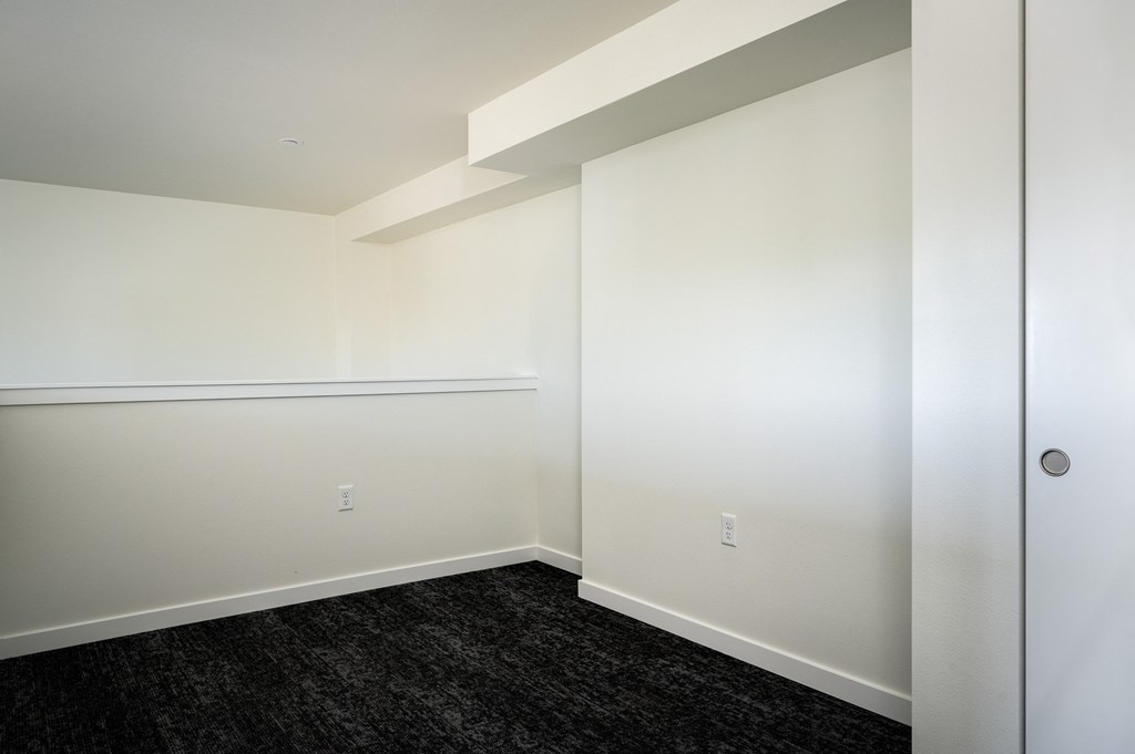 loft space with white walls and dark hardwood flooring