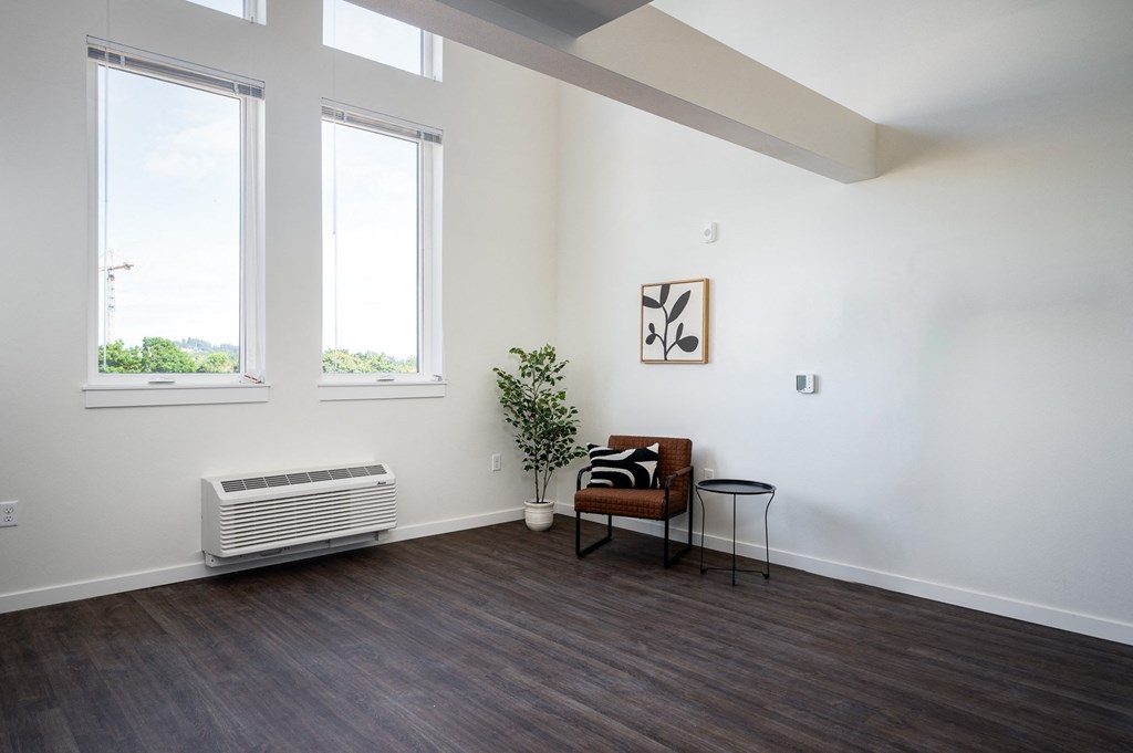 a living room with a chair, large windows and high ceilings