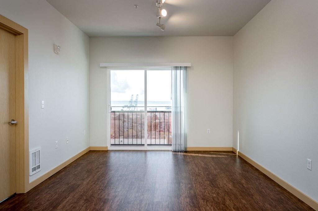 an empty living room with wood flooring and a large window