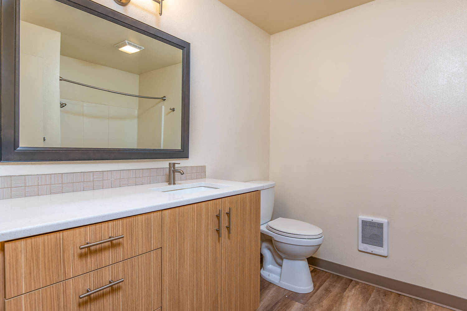 Bathroom with wood cabinetry, large mirror and toilet