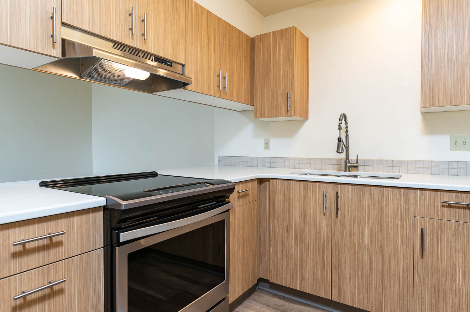 Beautiful Kitchen with wood cabinets, black and stainless stove, stainless faucet and cabinet hardware