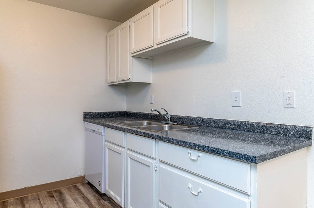 A kitchen with white cabinets and a granite countertop.