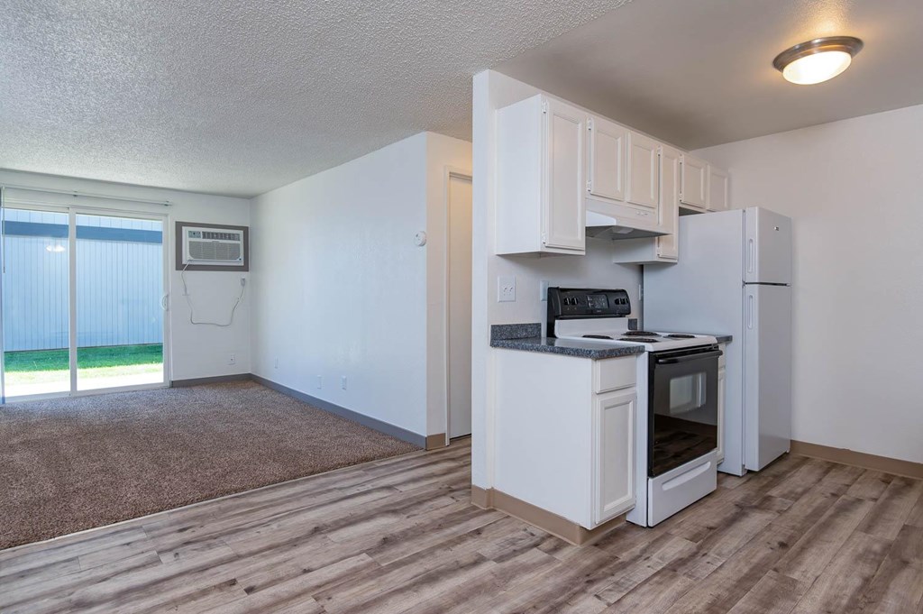 A kitchen with white appliances and a microwave on the counter.
