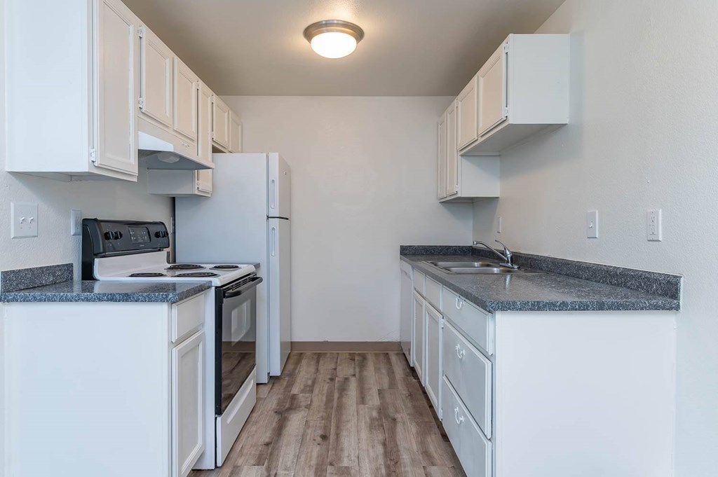 A kitchen with white cabinets and a granite countertop.