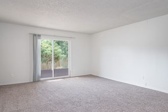 an empty living room with a sliding glass door to a patio