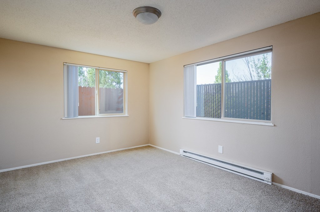 an empty living room with two windows and carpet