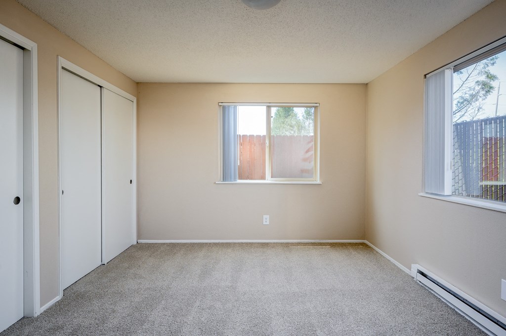 an empty bedroom with two closets and a window